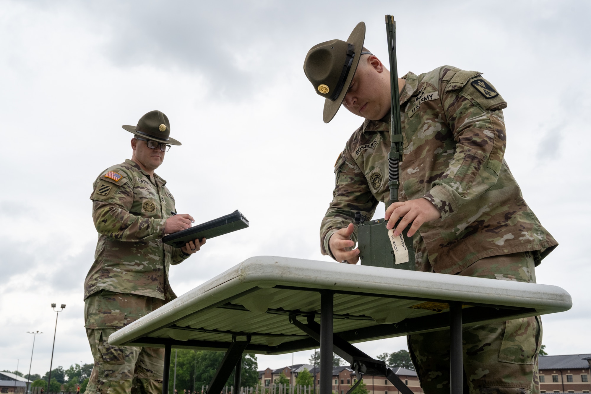 A man puts together a radio while another man watches.