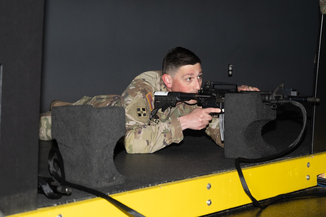 A man lays down while holding a rifle.