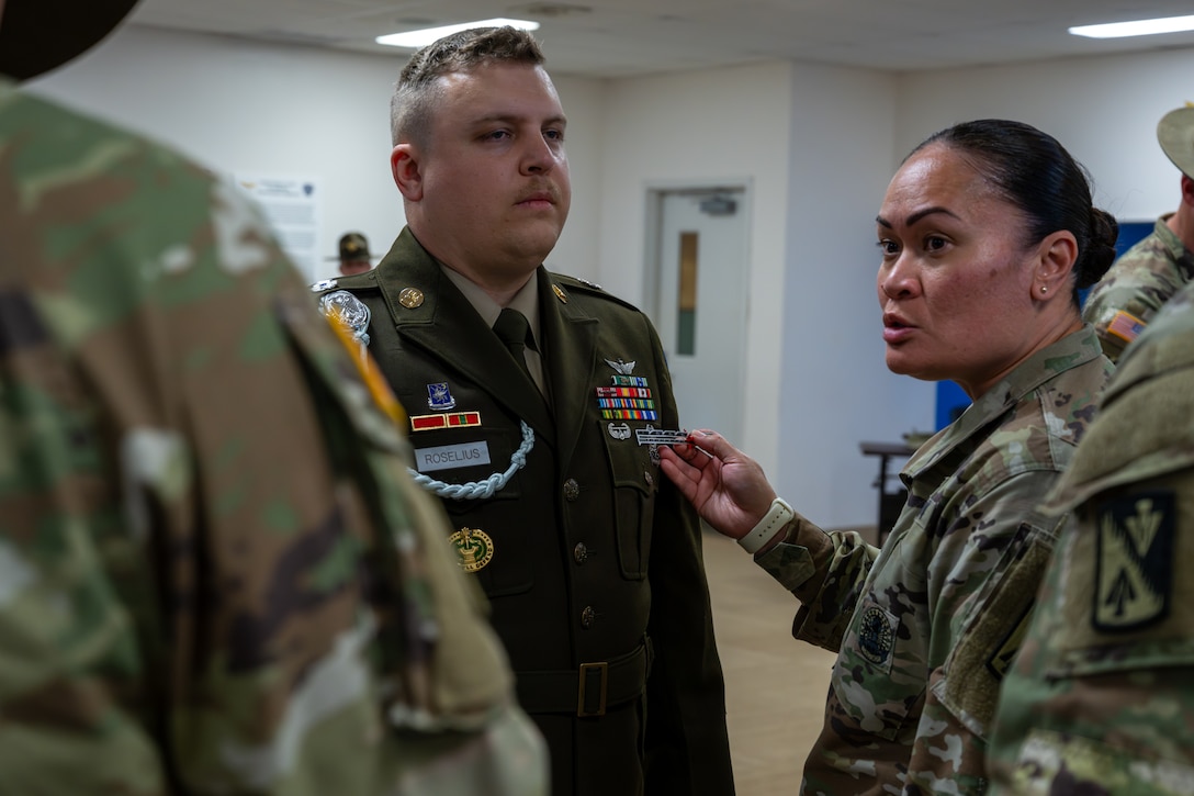 A woman holds a ruler up to a man's uniform.
