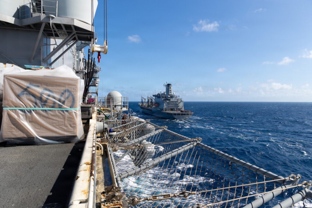 A large ship sails behind another ship in the ocean.