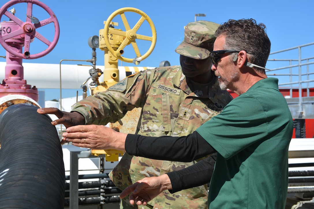 Two people observe a pipeline.