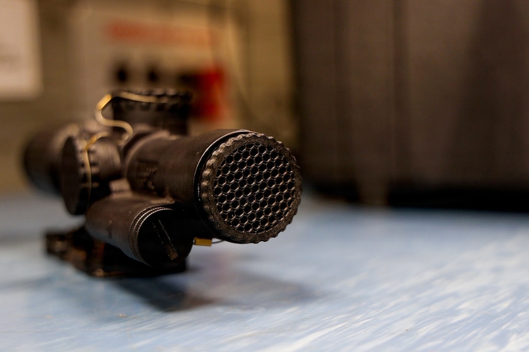 An optic sits on a counter with a 3D printed honeycomb fixture attached