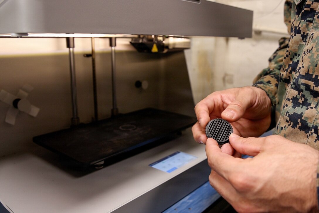 A Marine holds a 3D printed honeycomb fixture for a rifle mounted optic