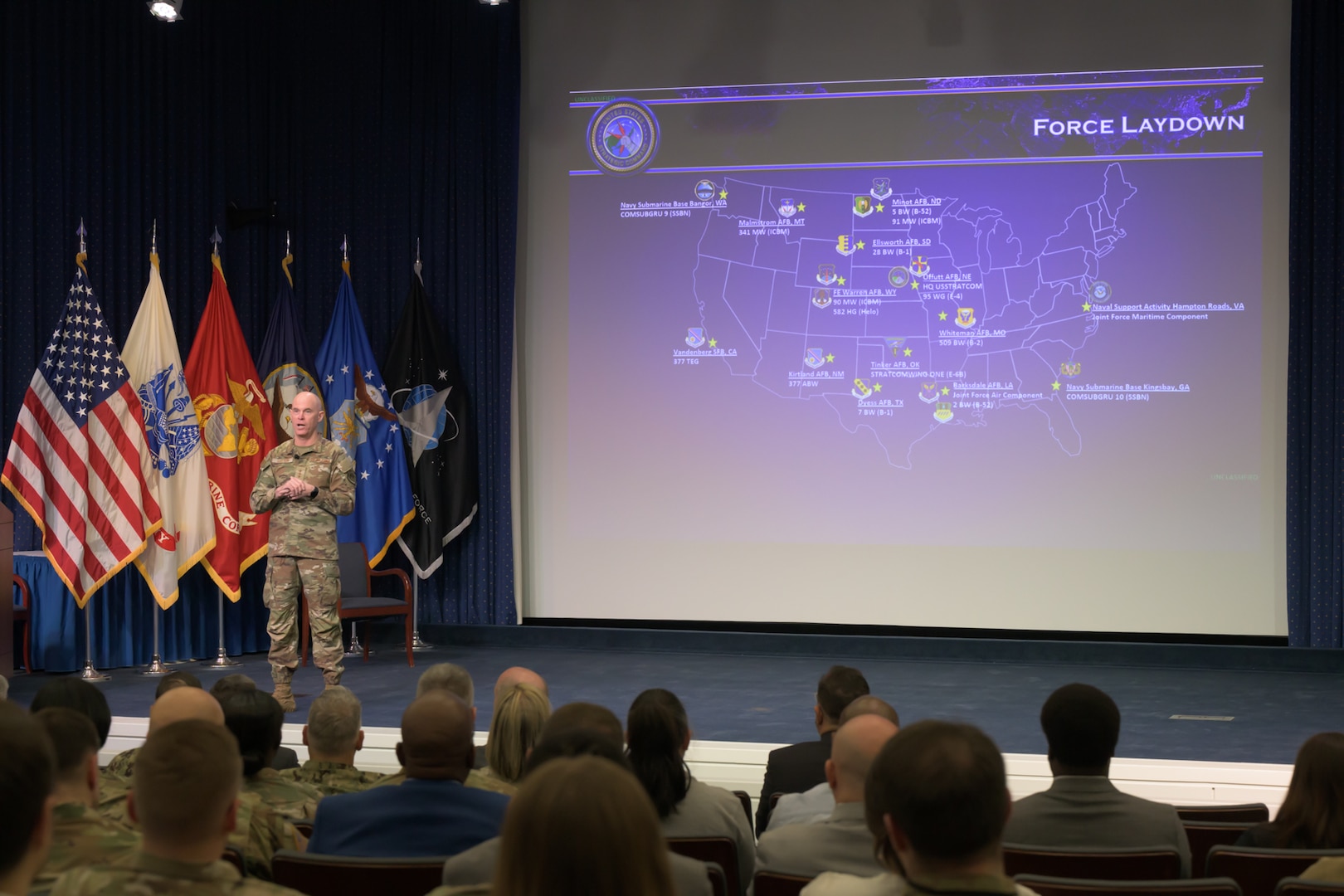 Man in Air Force uniform stands in front of a projected screen