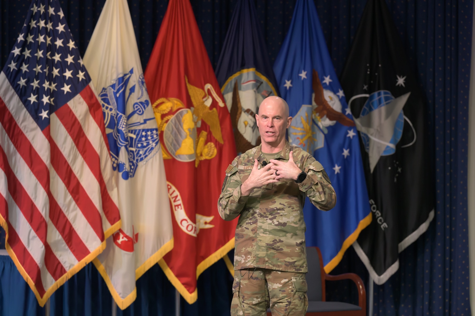 Man in Air Force uniform stands in front of flags