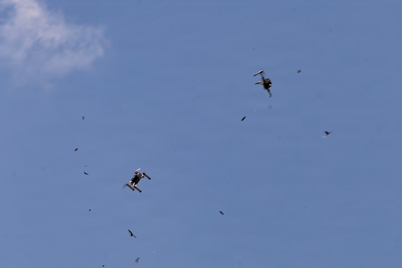 Two large drones and several smaller aerial practice targets fly in a blue sky.