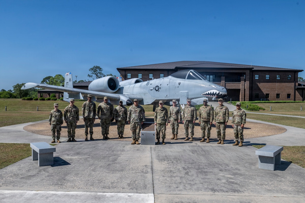 A group of military members standing in front of a A-10 Thunderbolt II.