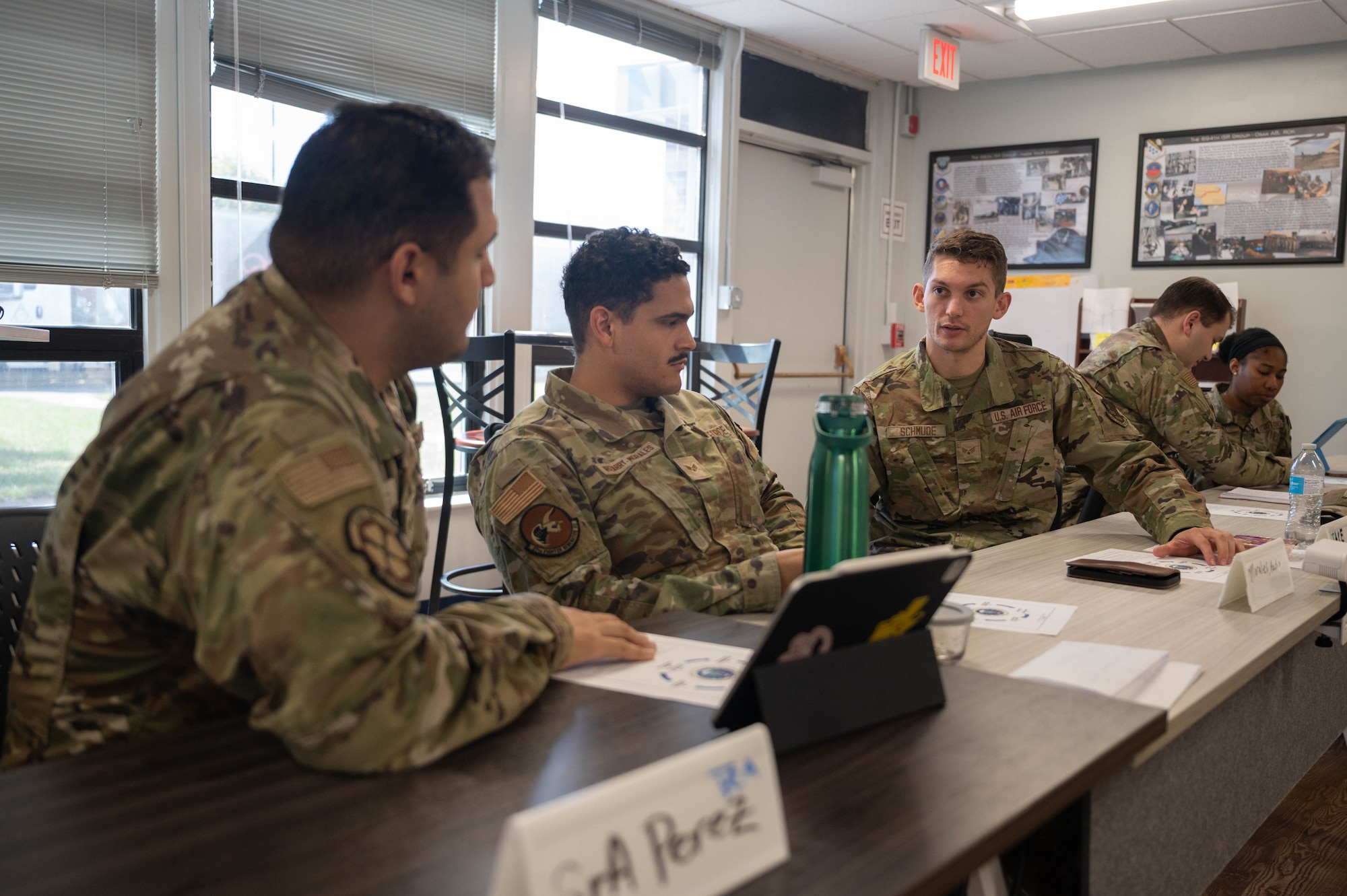 U.S. Airmen sit at a long table in a classroom.