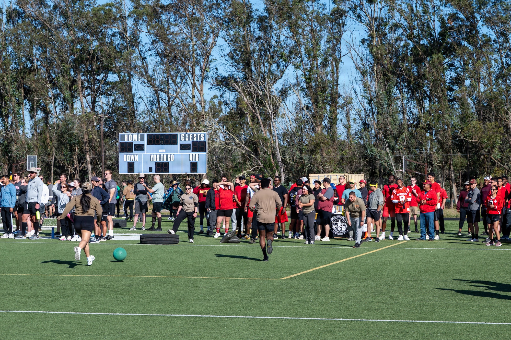 People run and play outside on a turf field.