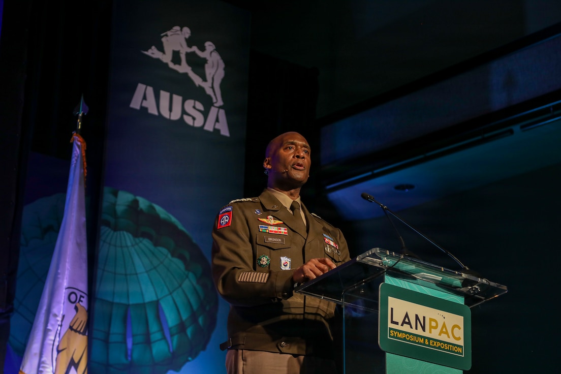 U.S. Army Gen. Xavier T. Brunson stands at a podium delivering a keynote address during the LANPAC Symposium in Honolulu, Hawaii, on May 12, 2026. Event signage and attendees are visible in the background at the professional development forum.