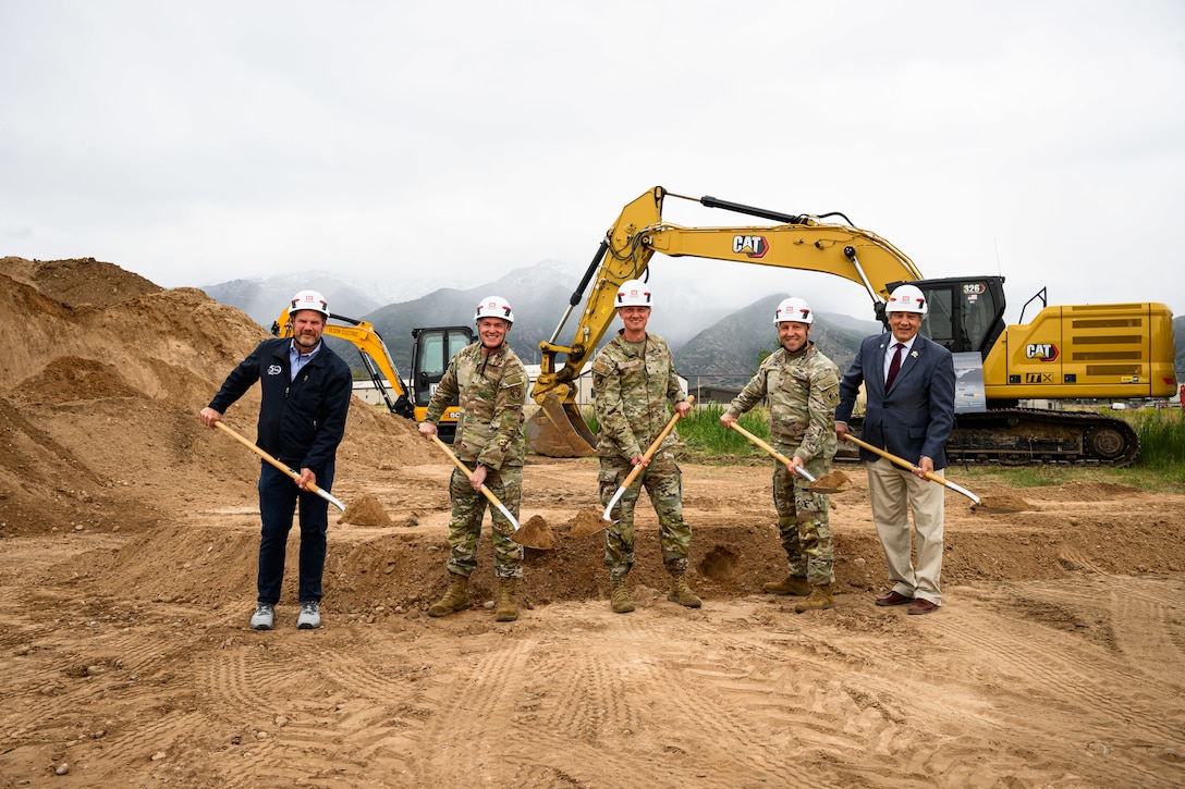 Members standing in a line holding shovels filled with dirt.