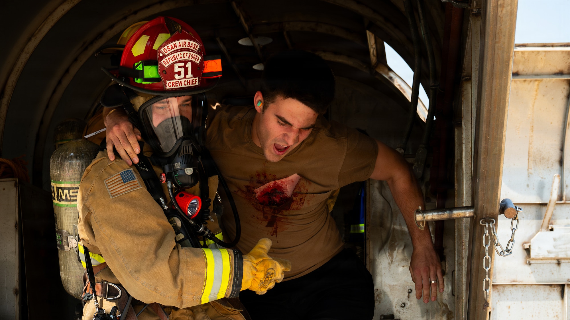 A firefighter assigned to the 51st Civil Engineer Squadron helps carry an injured person with a tear in his shirt and an exposed chest wound during a major accident response exercise as part of exercise Mustang Rodeo 26-2 at Osan Air Base, Republic of Korea, May 14, 2026.