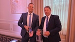 Two people holding awards at a ceremony.