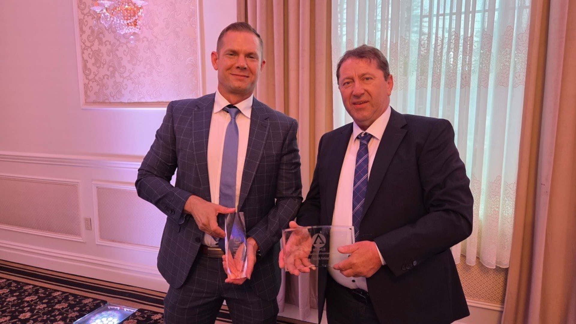 Two people holding awards at a ceremony.