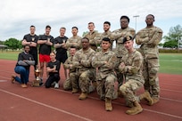 Airmen pose with arms crossed on a red rubber track.