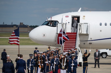 The Joint Service Color Guard and cordon present arms during a departure ceremony, while King Charles III waves goodbye.
