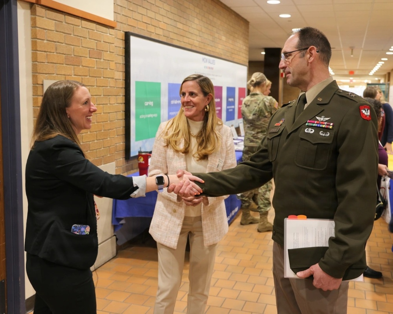 Shaking hands in a hallway full of smiling people