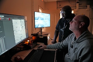 Photo shows two men looking at computer.