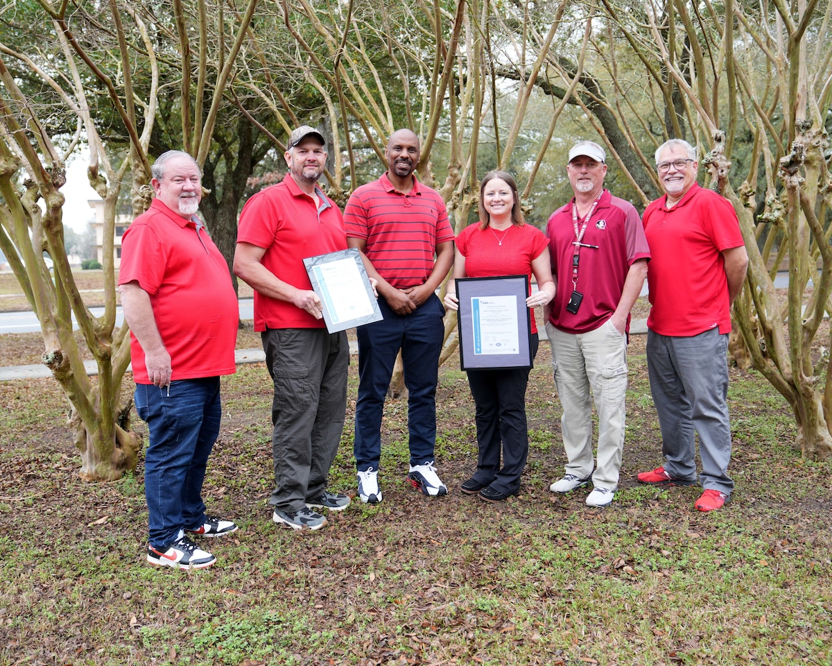 Photo shows group of six people holding two certificates