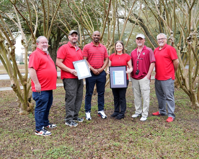 Photo shows group of six people holding two certificates
