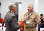 SAN ANTONIO – (May 18, 2026) – U.S. Navy Capt. Michael Tiller, commanding officer, Naval Medical Research Unit (NAMRU) San Antonio, speaks with John Lamberton of the DLH Corporation at the Defense Health Agency’s annual Promote Professional Engagement amongst Military Laboratories (ProPEL) Science Symposium held at the VelocityTX Innovation Center. The event brought together military medical professionals, researchers, students, and academic partners to explore the latest in defense health innovation.  Attendees at ProPEL heard from several San Antonio Centers of Excellence to include research presentations on Battlefield/Point of Injury, Prolonged Field Care/Early Interventions, and Integrated Rehabilitation and Human Performance. Collaborating and working alongside a wide range of research and development partners keeps Navy Medicine Research & Development (NMR&D) abreast of best practices and advances in medical knowledge. NAMRU San Antonio, part of NMR&D conducts gap-driven combat casualty care, craniofacial, and directed energy research in support of Navy, Marine Corps and joint U.S. warfighter health readiness and lethality while engaged in routine and expeditionary operations. (Photo by Burrell Parmer, NAMRU San Antonio Public Affairs/Released)