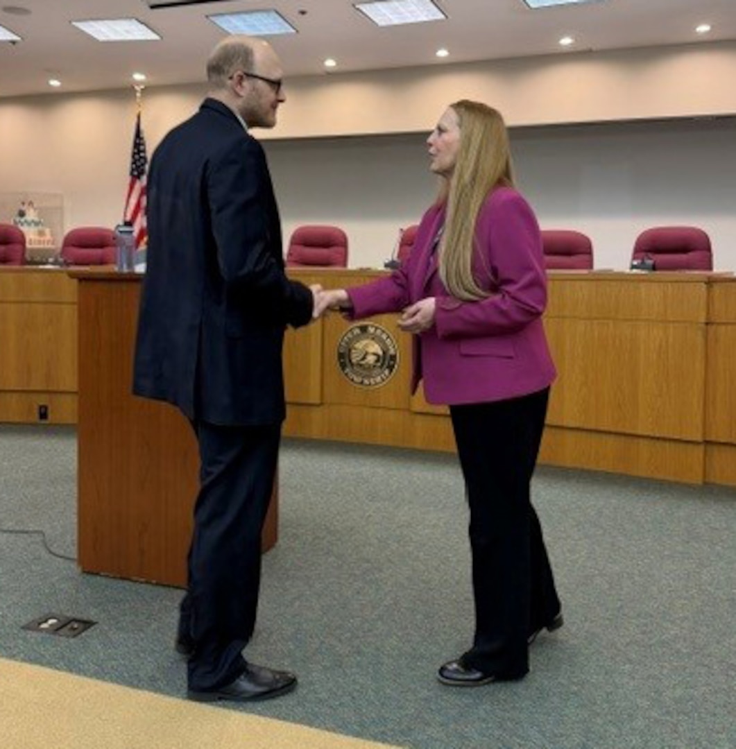 DCAA Director Jennifer Desautel shakes hands with employee receiving Director coin.