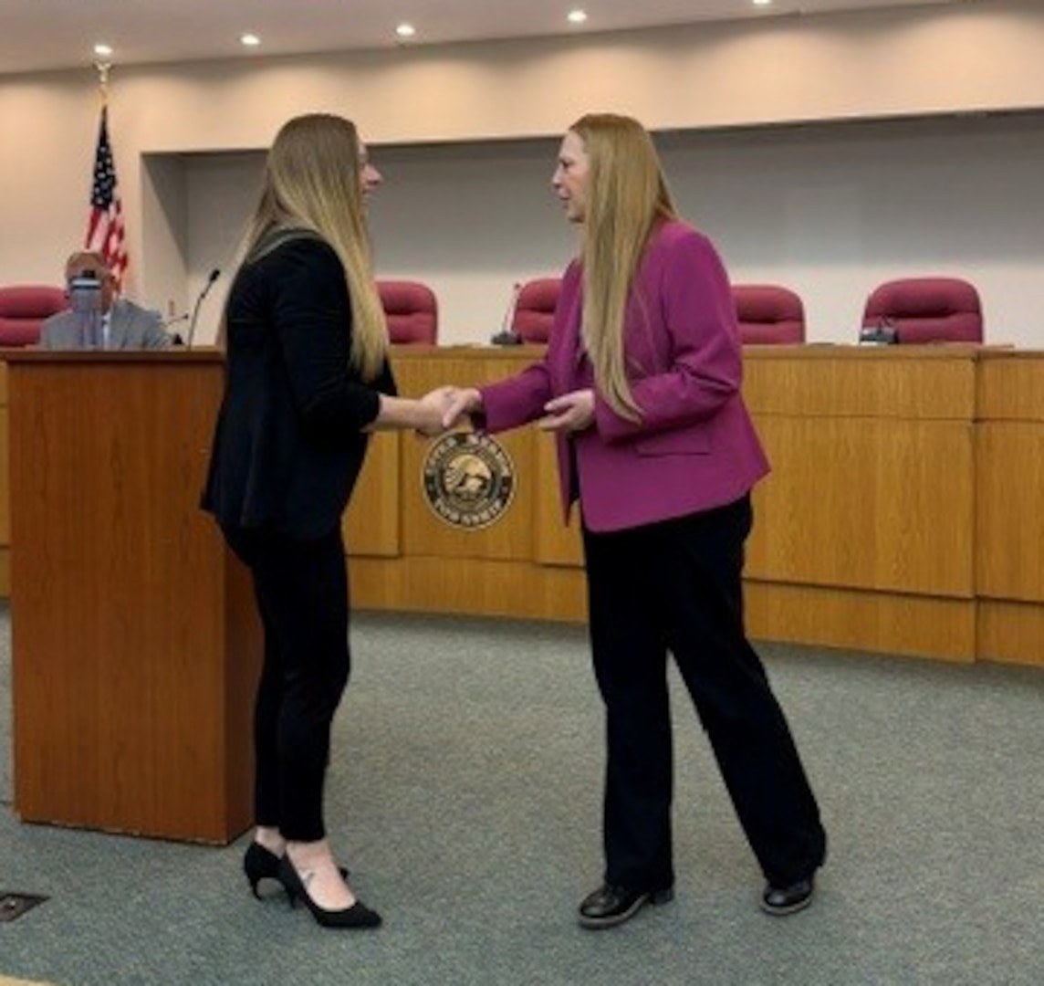 DCAA Director Jennifer Desautel shakes hands with employee receiving Director coin.