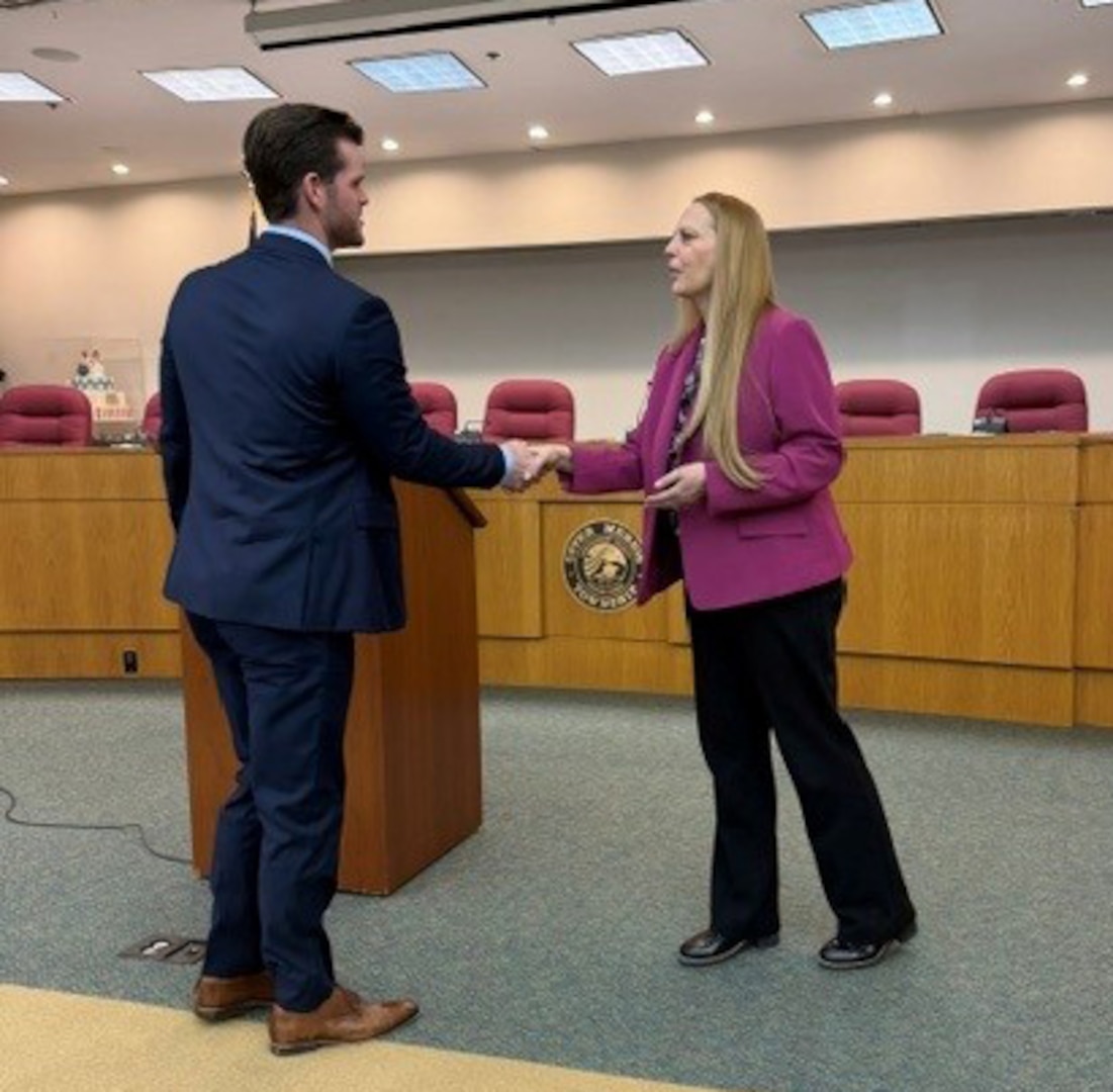 DCAA Director Jennifer Desautel shakes hands with employee receiving Director coin.
