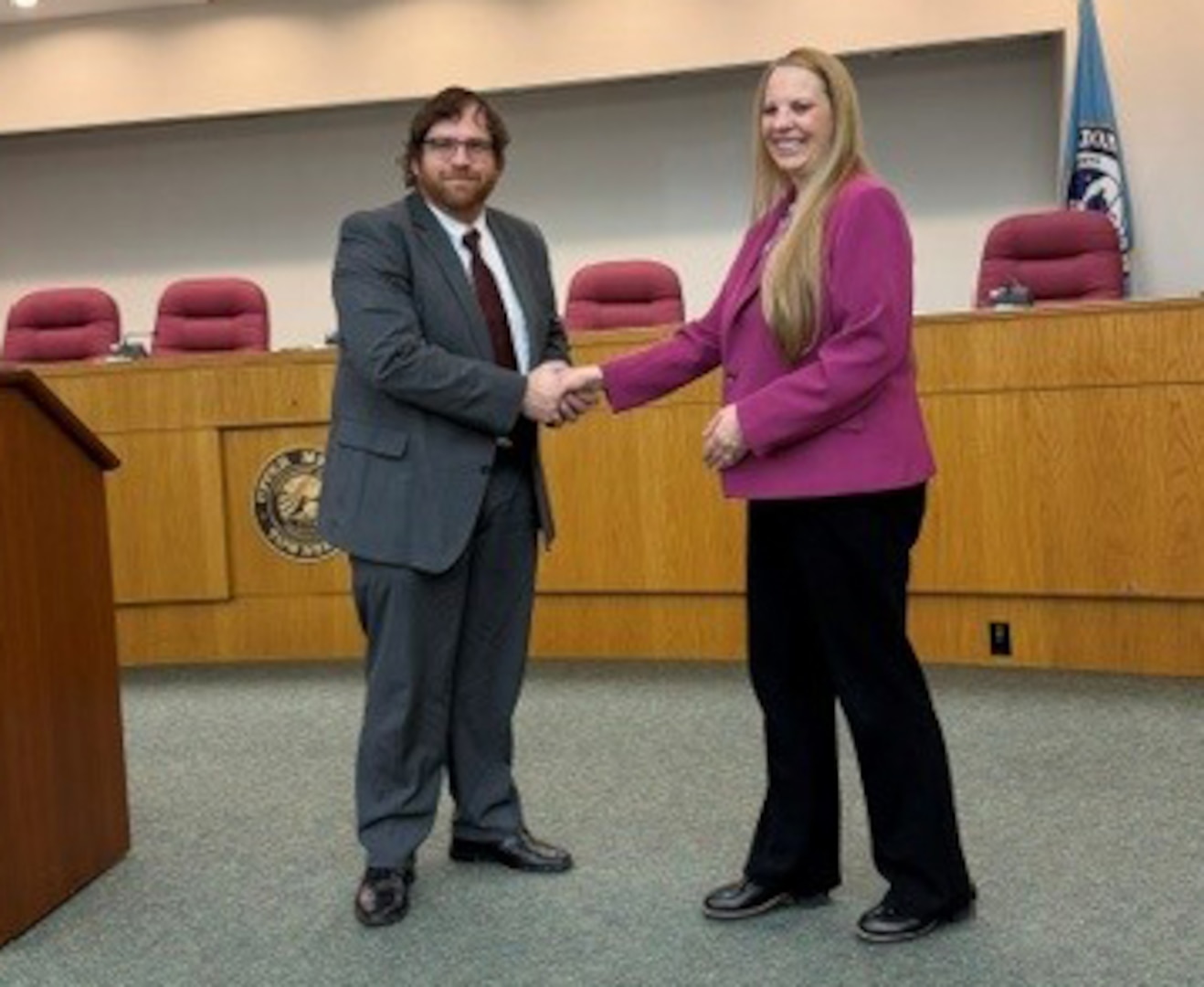 DCAA Director Jennifer Desautel shakes hands with employee receiving Director coin.