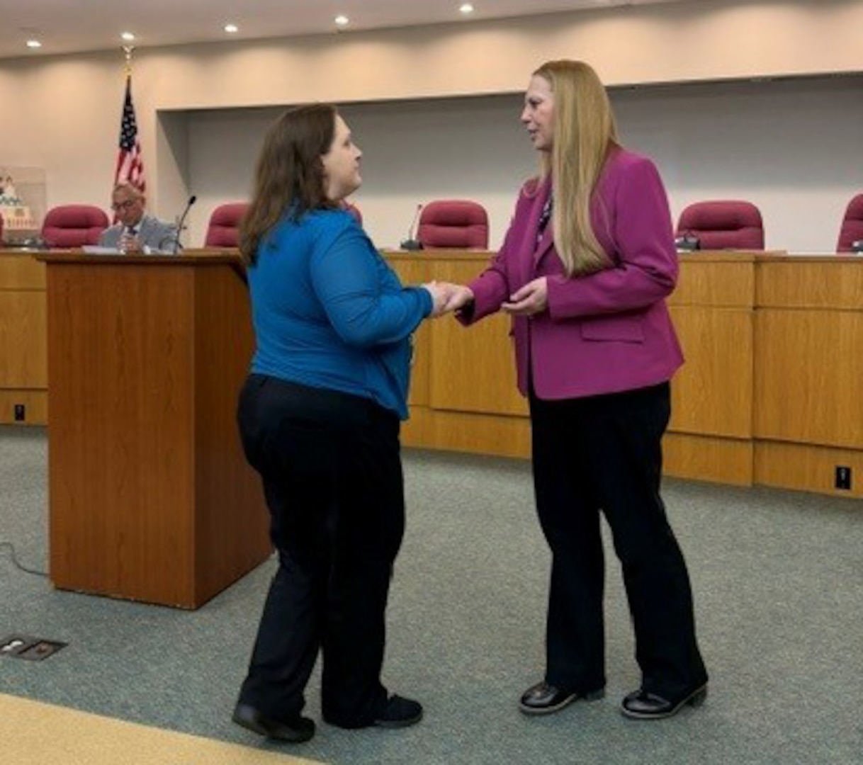 DCAA Director Jennifer Desautel shakes hands with employee receiving Director coin.