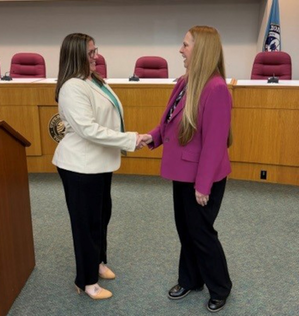 DCAA Director Jennifer Desautel shakes hands with employee receiving Director coin.