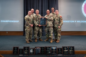 six uniformed men hold an award on a stage