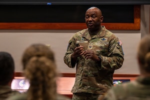 A person stands and speaks to people sitting in an auditorium.