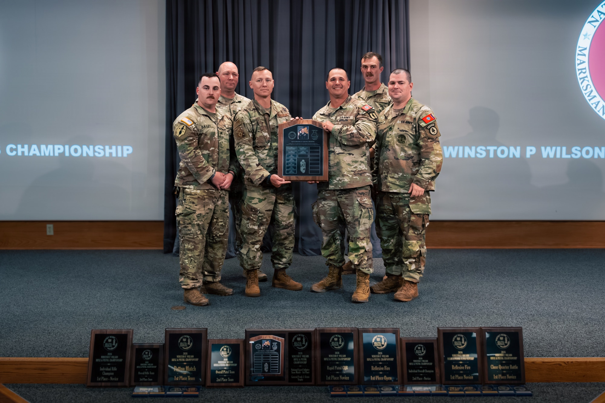 six uniformed men hold an award on a stage