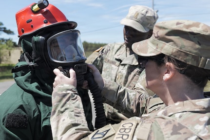 U.S. Soldiers aid Sgt. Josiah McBride, left, serving as part of the Massachusetts National Guard Chemical, Biological, Radiological and Nuclear, or CBRN, Task Force Search and Extraction Recon Team 1 in donning personal protective equipment during a CBRN Task Force collective training exercise at Camp Edwards Training Site, Joint Base Cape Cod, Massachusetts, May 16, 2026.