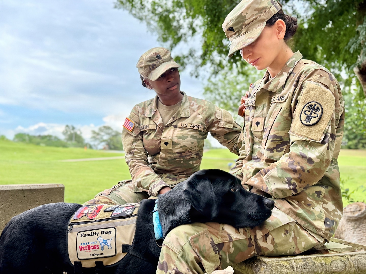 Two Soldiers pose with a service dog.