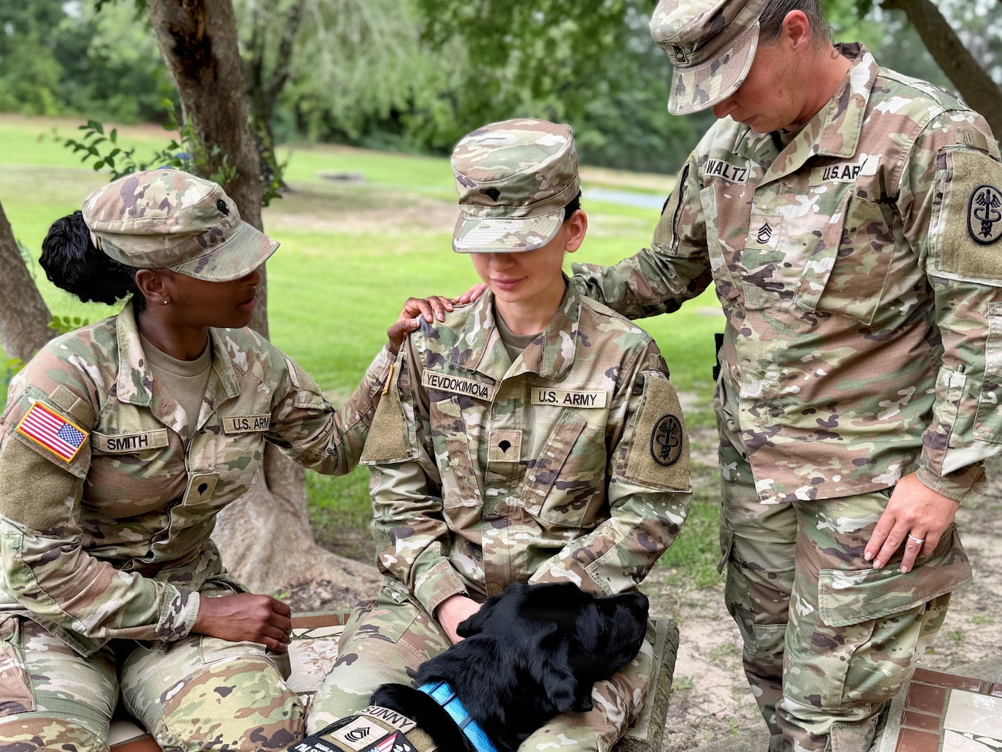 Three Soldiers pose with a service dog.
