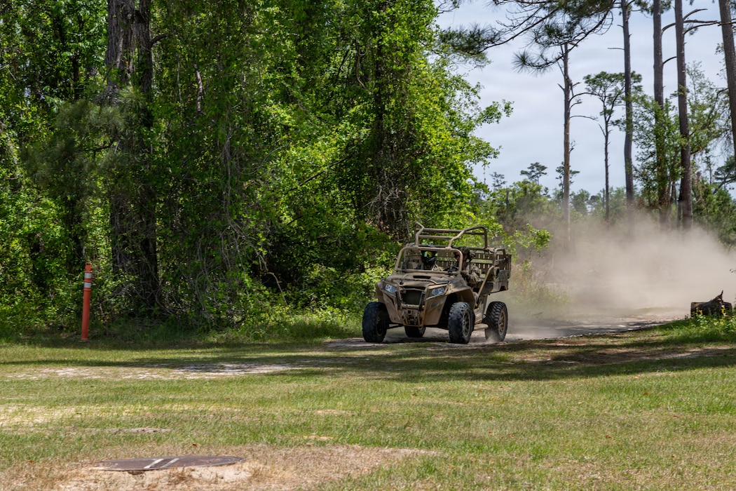 An all-terrain vehicle driving blowing dust behind them.