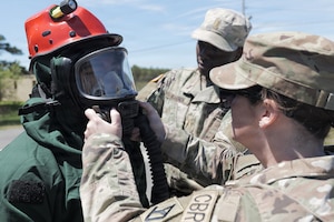 U.S. Soldiers aid Sgt. Josiah McBride, left, serving as part of the Massachusetts National Guard Chemical, Biological, Radiological and Nuclear, or CBRN, Task Force Search and Extraction Recon Team 1 in donning personal protective equipment during a CBRN Task Force collective training exercise at Camp Edwards Training Site, Joint Base Cape Cod, Massachusetts, May 16, 2026.