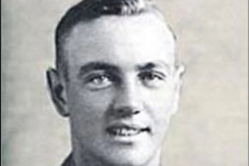 A man in a formal military uniform smiles for a portrait.