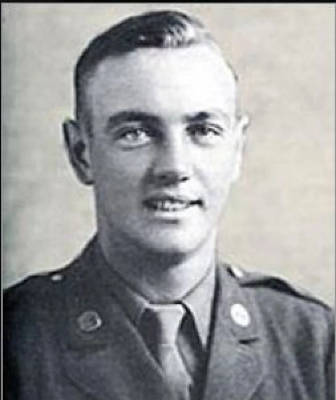 A man in a formal military uniform smiles for a portrait.