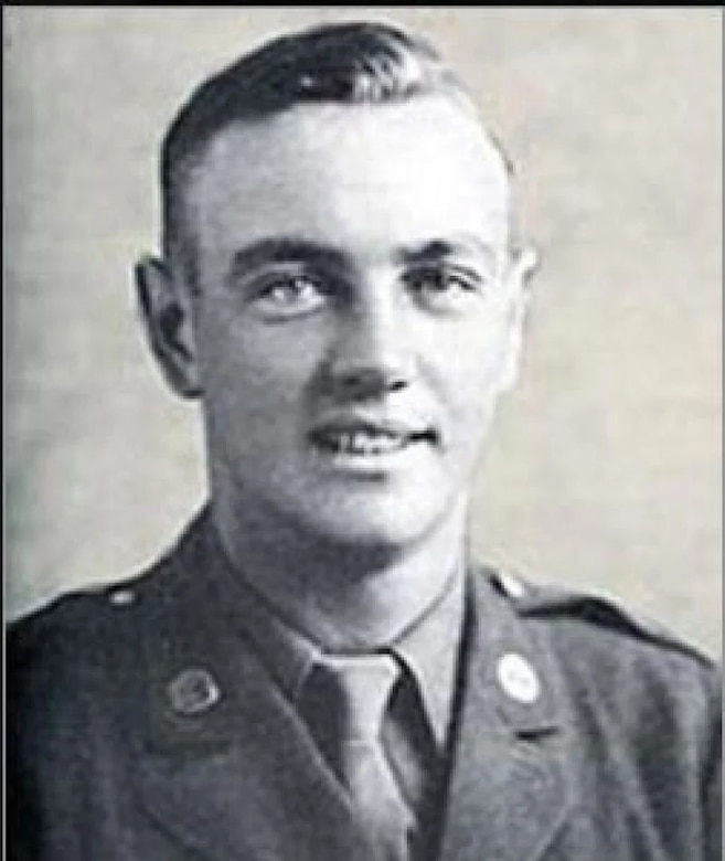 A man in a formal military uniform smiles for a portrait.