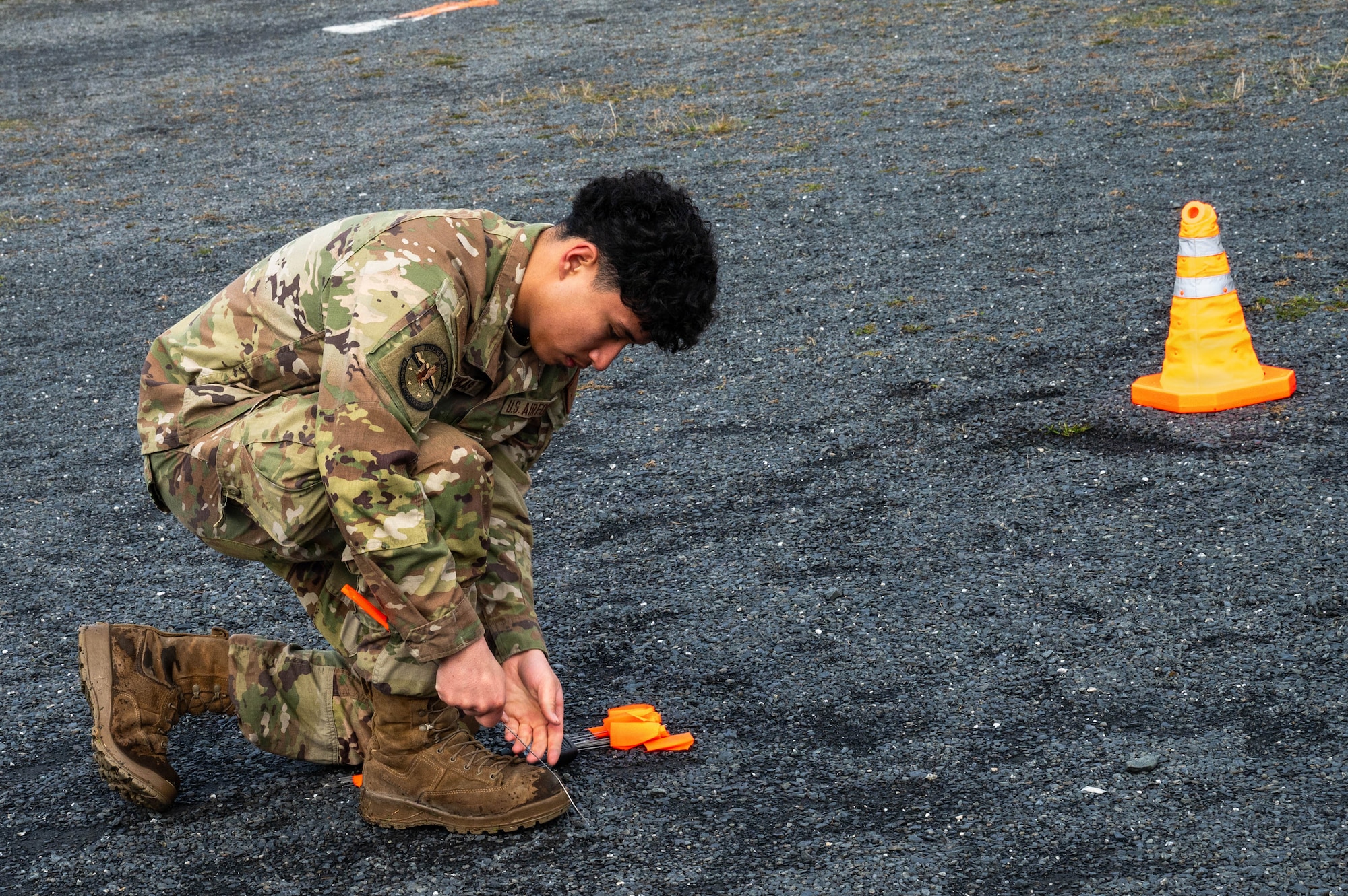 U.S. Air Force Airman 1st Class Andres Chicas, 773 Civil Engineer Squadron Heating, Ventilation, and Air Conditioning technician, uses flags to mark an area surrounding a simulated unexploded ordnance in a post-attack reconnaissance and recovery scenario during exercise Tropic Tundra 26 at Coast Guard Air Station Kodiak, Alaska, May 14, 2026.