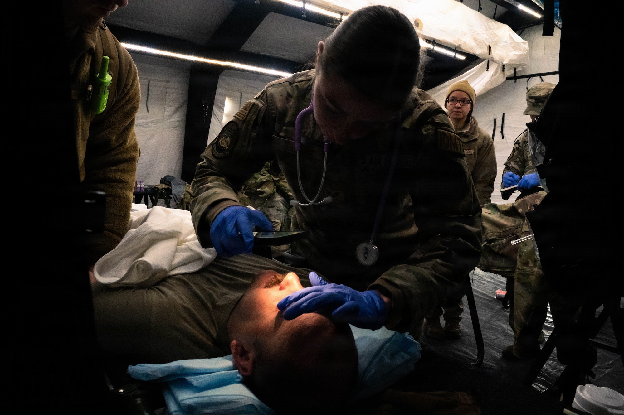 U.S. Air Force Senior Airman Storrm Yaggie, 525th Fighter Squadron independent duty medical technician, checks the pupils of Capt. Logan Loomis, 525th FS flight surgeon, in a post-attack reconnaissance and recovery scenario during exercise Tropic Tundra 26 at Coast Guard Air Station Kodiak, Alaska, May 14, 2026.