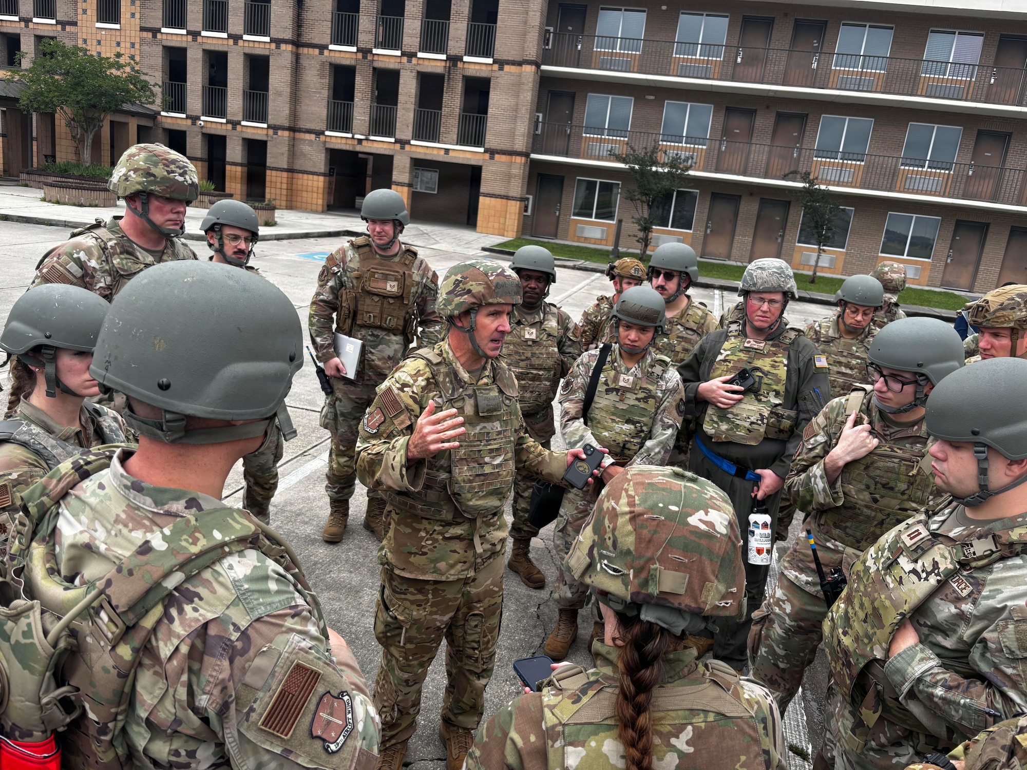 military members are huddled in a circle while one member stands in the middle speaking.