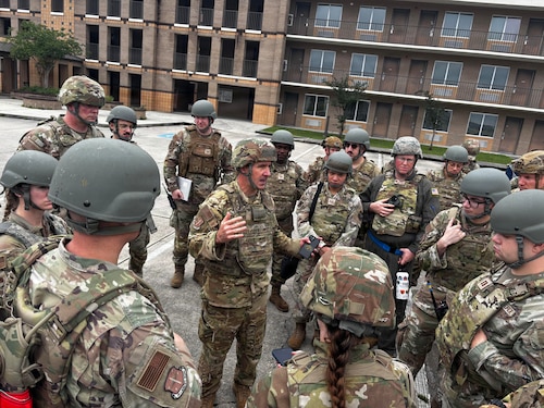 military members are huddled in a circle while one member stands in the middle speaking.