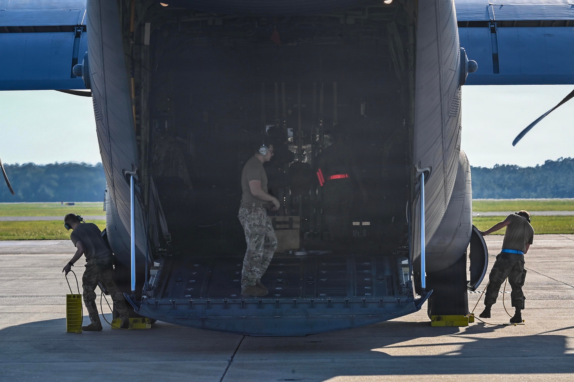 Military members stand in the back of a c-130 aircraft.