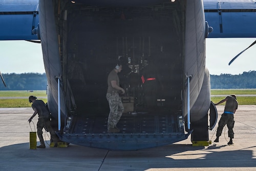 Military members stand in the back of a c-130 aircraft.