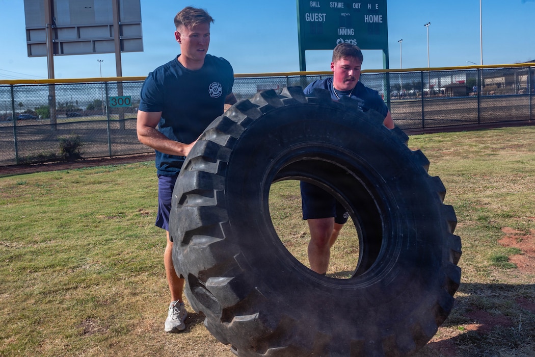 U.S. Air Force Staff Sgt. Travis Leonard, 56th Civil Engineer Squadron fire crew chief, left, and Airman Andrew Baird, 56th CES firefighter, flip a tire as part of the defenders challenge held during 2026 Police Week at Luke Air Force Base, Arizona, May 11, 2026. Base personnel were invited to join law enforcement officers in the defender challenge which served to honor tradition, precision, and the spirit of service of law enforcement members in support of the partnerships and communities they serve. (U.S. Air Force photo by Airman 1st Class Tekorey Watkins)