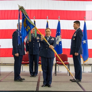 Female air force officer in dress blue uniform presenting 127th Wing guidon to the audience on stage